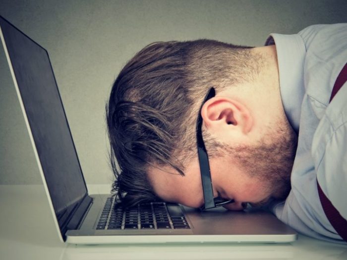 man with head down on laptop looking broken